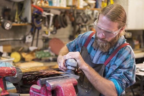 Caucasian craftsman grinding in workshop