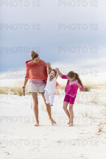 Caucasian mother and children walking on sand dune