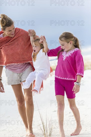 Caucasian mother and children playing on sand dune