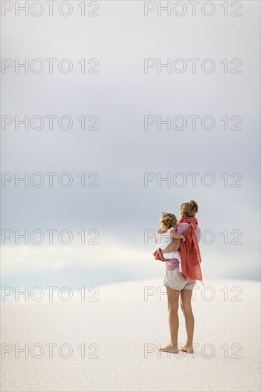 Caucasian mother holding son on sand dune