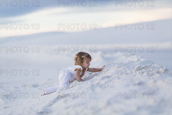 Caucasian boy climbing sand dune