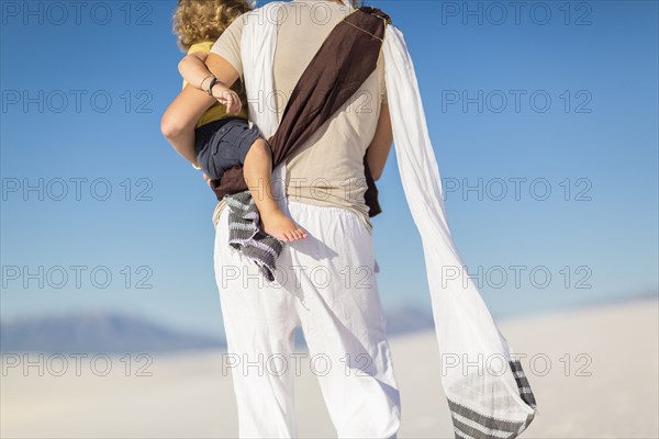 Caucasian mother holding son on sand dune