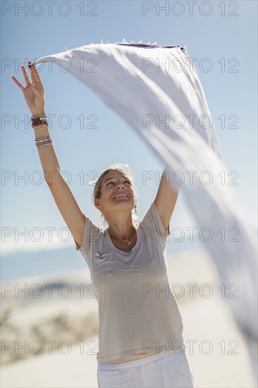 Caucasian woman playing with scarf on sand dune