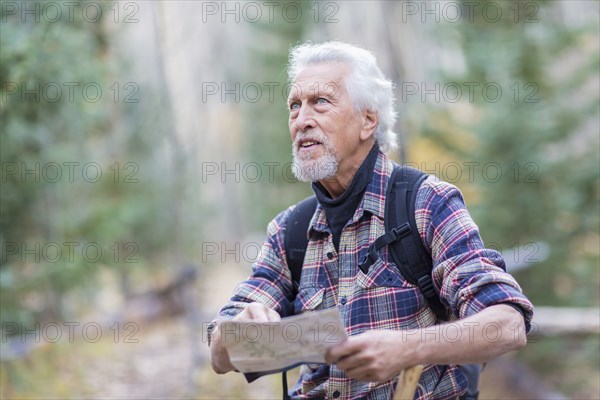 Caucasian hiker reading map in forest
