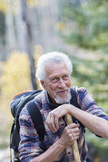Caucasian hiker leaning on walking stick in forest