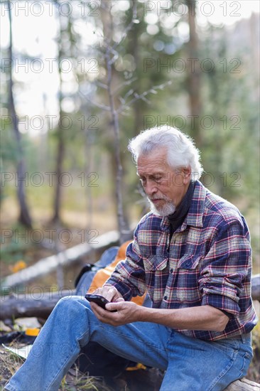 Caucasian hiker using cell phone in forest