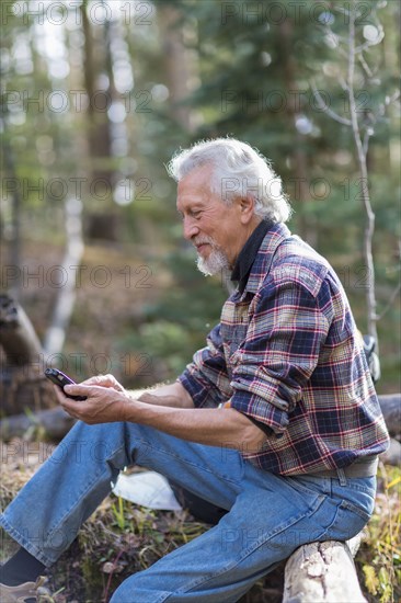 Caucasian hiker using cell phone in forest