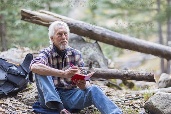 Caucasian hiker writing in forest