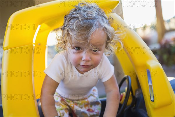 Caucasian boy playing in toy car