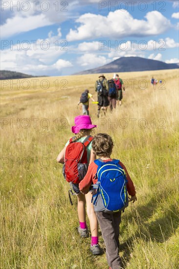 Caucasian children walking in grassy field in remote landscape