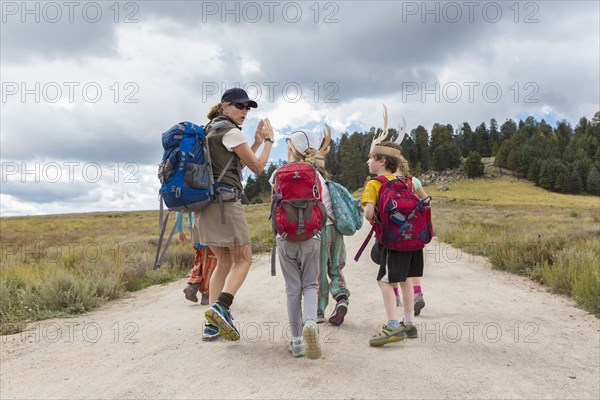 Caucasian hiker leading children on path in remote landscape