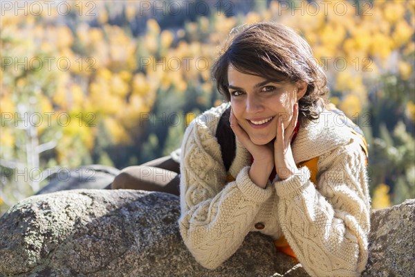 Mixed race woman smiling on rock