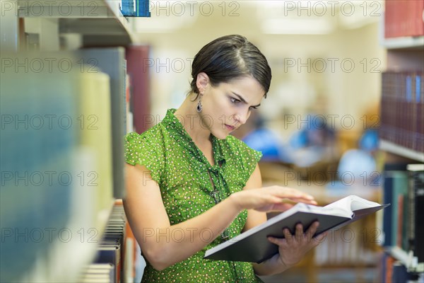 Mixed race student reading book in library