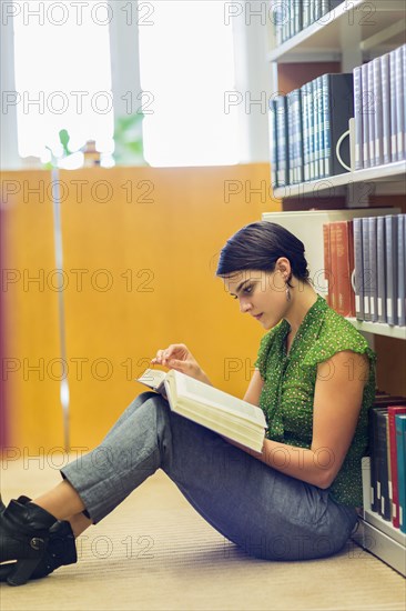 Mixed race student reading book in library