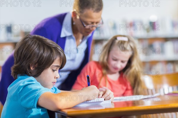 Student writing in notebook in library