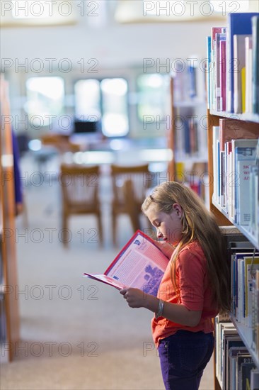 Caucasian student reading book in library