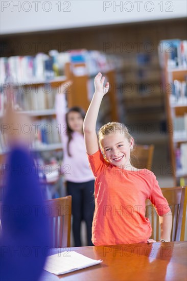 Student raising her hand in library