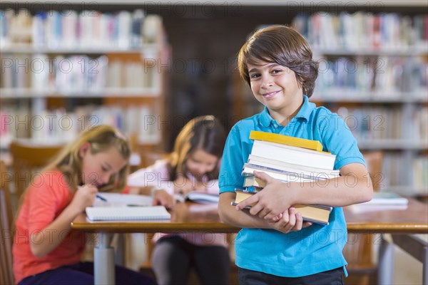 Student carrying stack of books in library