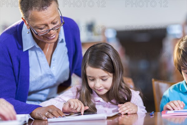 Teacher helping student use digital tablet in library