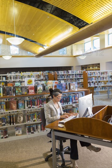 Hispanic woman using computer in library