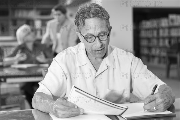 Caucasian man writing on notepad in library