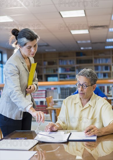 Teacher helping adult student in library