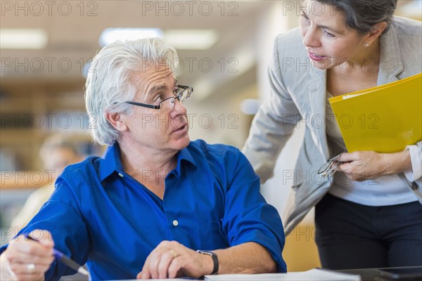 Teacher helping adult student in library