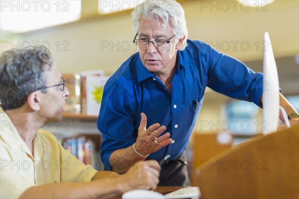 Teacher helping adult student in library