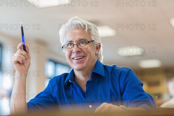 Hispanic adult student raising his hand in class