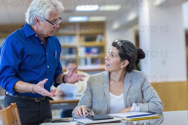 Teacher helping adult student in library