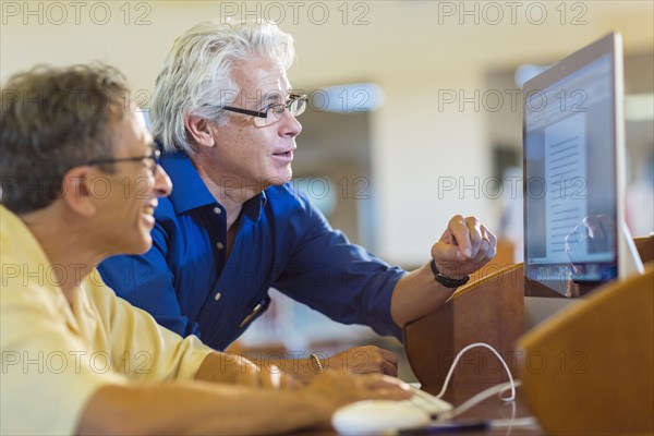 Teacher helping adult student use computer in library