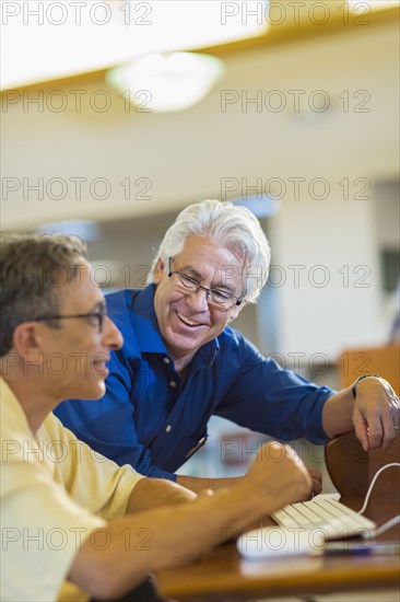 Teacher helping adult student use computer in library