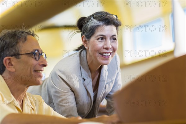 Teacher helping adult student use computer in library