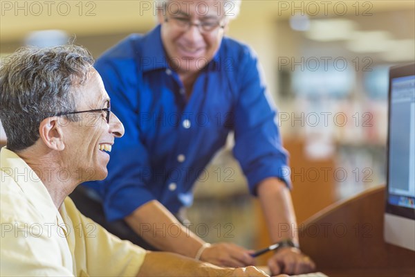 Teacher helping adult student use computer in library