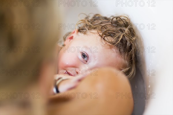 Caucasian mother nursing baby son in bath