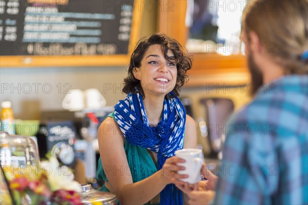 Server giving cup of coffee to customer in cafe