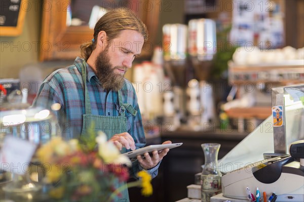 Caucasian server using digital tablet in cafe