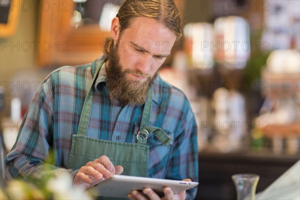 Caucasian server using digital tablet in cafe