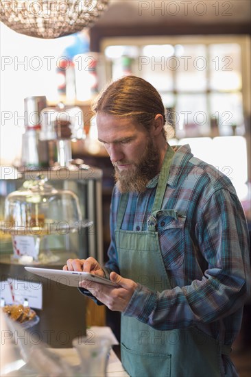 Caucasian server using digital tablet in cafe