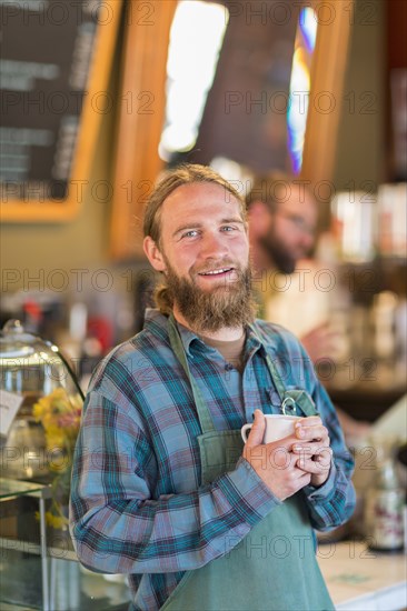 Caucasian server drinking cup of coffee in cafe