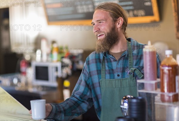 Caucasian server holding cup of coffee in cafe