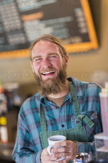 Caucasian server holding cup of coffee in cafe