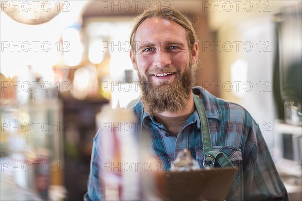Caucasian server holding clipboard in cafe