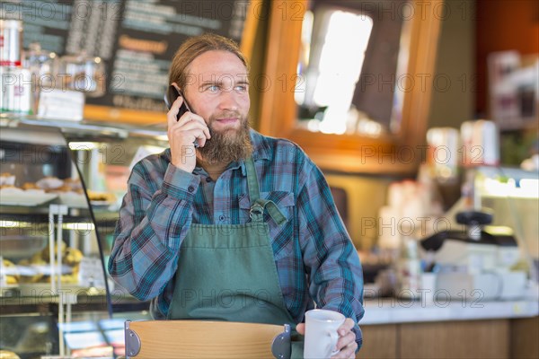 Caucasian server talking on telephone in cafe