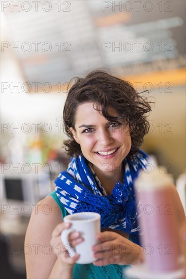 Mixed race woman holding cup of coffee in cafe