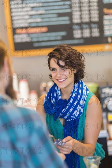 Mixed race cashier talking to customer in cafe