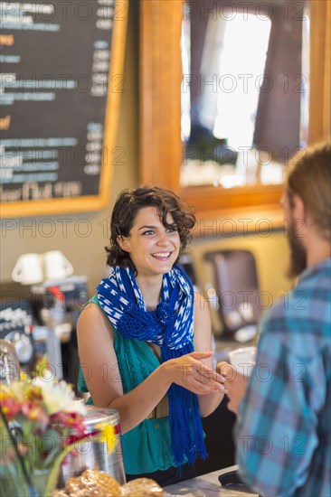 Mixed race server talking to customer in cafe