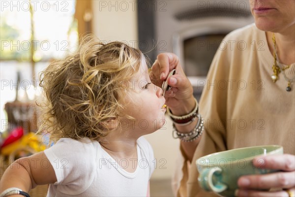 Caucasian mother feeding baby son in high chair