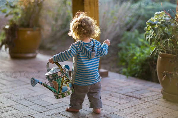 Caucasian baby carrying watering can