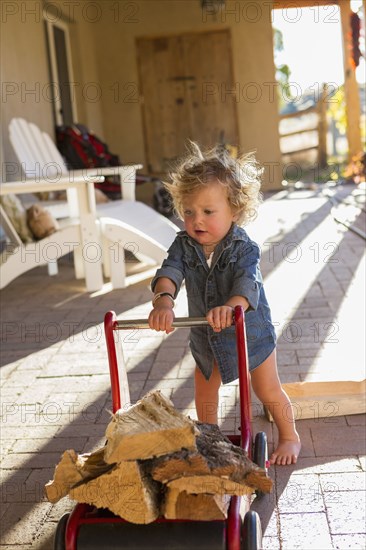 Caucasian baby pushing firewood on toy cart